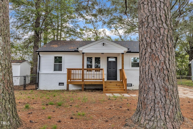 bungalow with crawl space, a shingled roof, covered porch, fence, and brick siding