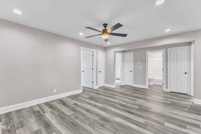 unfurnished bedroom with ensuite bathroom, baseboards, recessed lighting, a ceiling fan, and wood finished floors