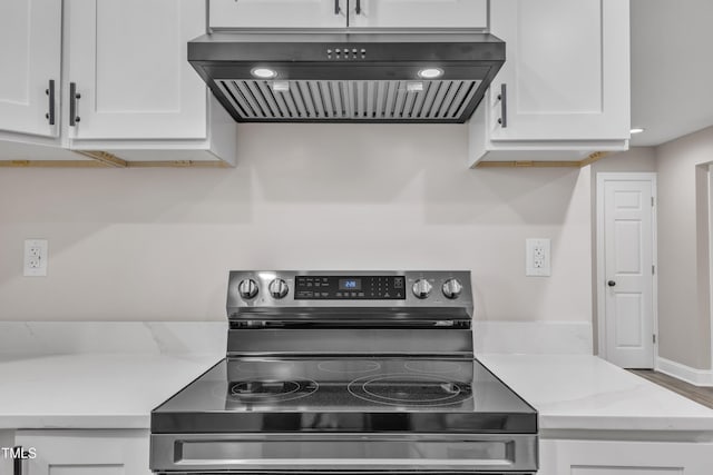 kitchen with stainless steel electric range, white cabinetry, and wall chimney range hood