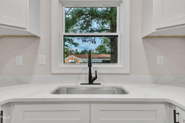 room details with light stone counters, white cabinetry, and a sink