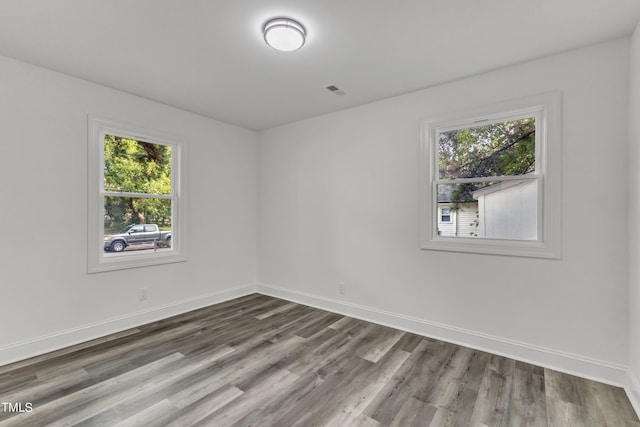 empty room with wood finished floors, a wealth of natural light, and baseboards