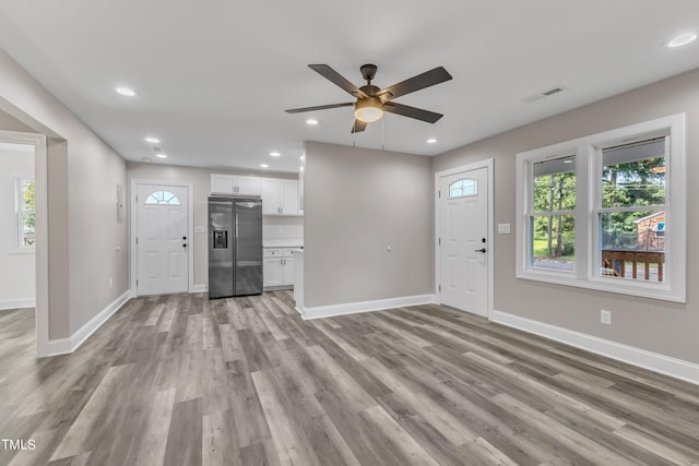 unfurnished living room with baseboards, visible vents, a ceiling fan, and a wealth of natural light