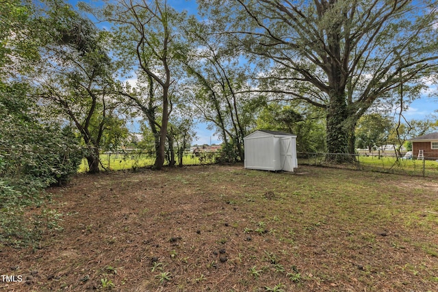 view of yard featuring a storage shed, a fenced backyard, and an outdoor structure