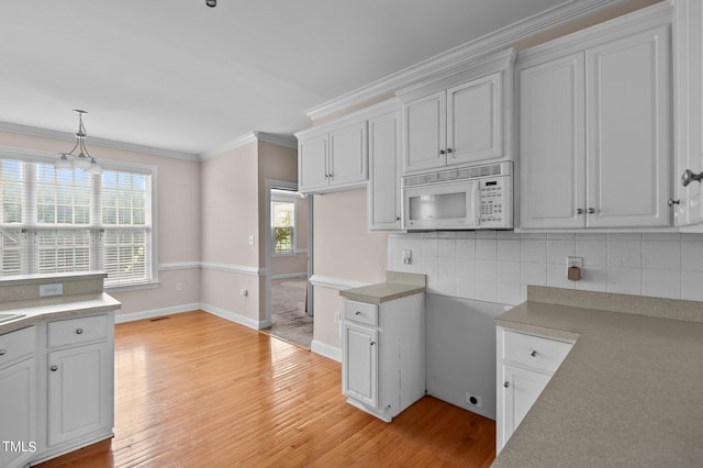 kitchen with light hardwood / wood-style flooring, white cabinetry, decorative light fixtures, and tasteful backsplash