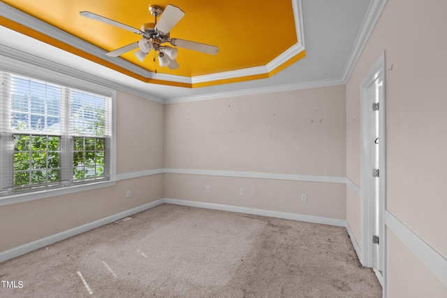 unfurnished room featuring light carpet, a tray ceiling, ornamental molding, and ceiling fan