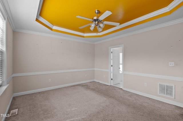 spare room featuring carpet floors, a tray ceiling, crown molding, and ceiling fan