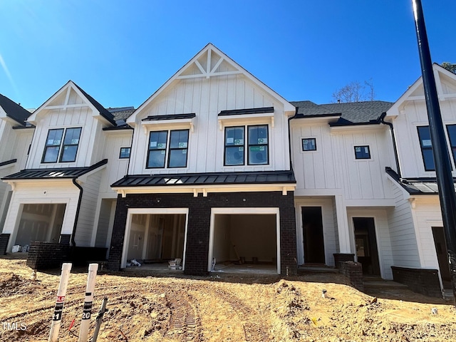 view of front of house with a garage, a standing seam roof, board and batten siding, and brick siding