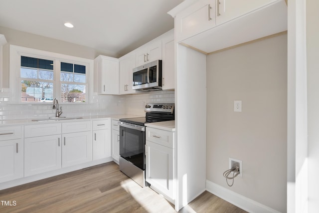 kitchen with white cabinets, light hardwood / wood-style floors, sink, and stainless steel appliances