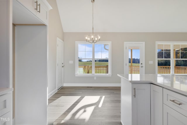 interior space featuring pendant lighting, vaulted ceiling, dark hardwood / wood-style floors, a notable chandelier, and white cabinetry