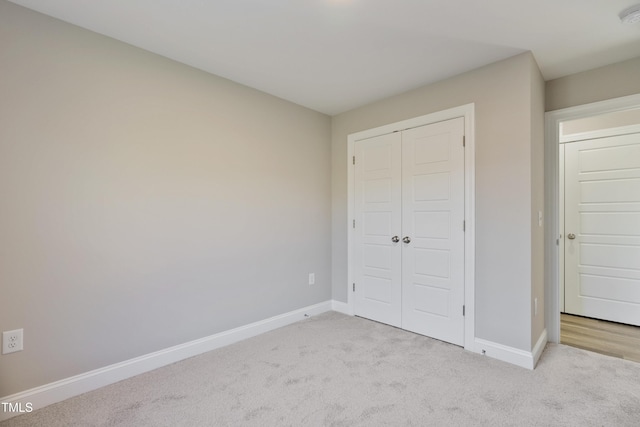 unfurnished bedroom with light carpet and a closet