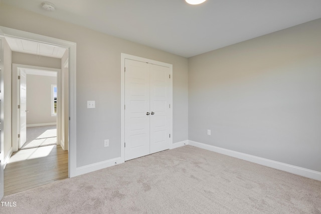 unfurnished bedroom featuring light carpet and a closet