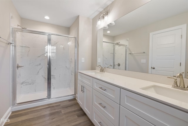 bathroom with wood-type flooring, vanity, and a shower with shower door