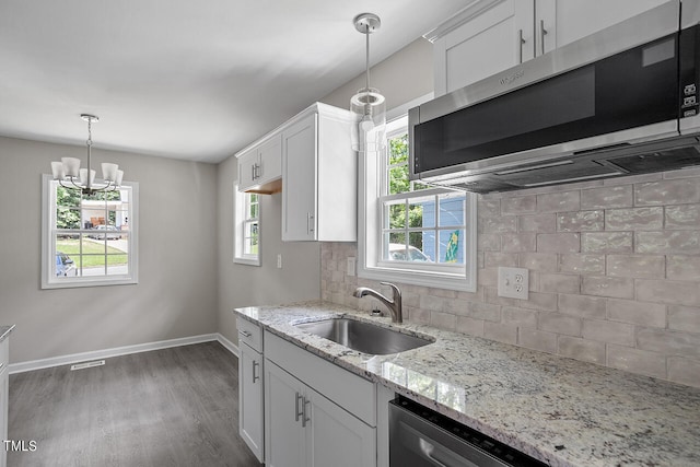 kitchen with appliances with stainless steel finishes, hanging light fixtures, white cabinetry, and tasteful backsplash