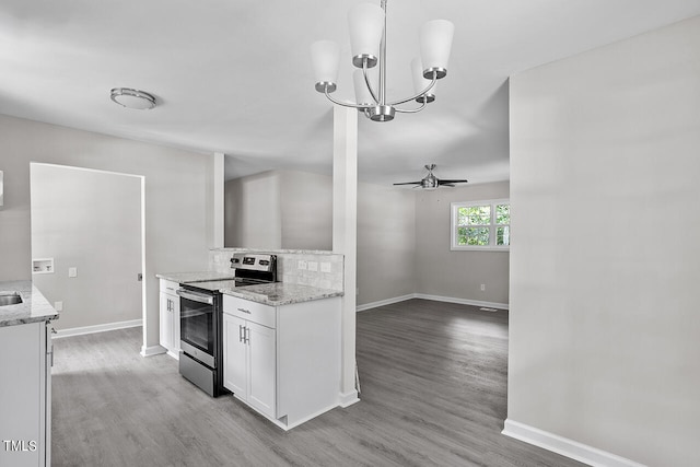 kitchen with light stone counters, white cabinets, hanging light fixtures, stainless steel electric range, and light wood-type flooring