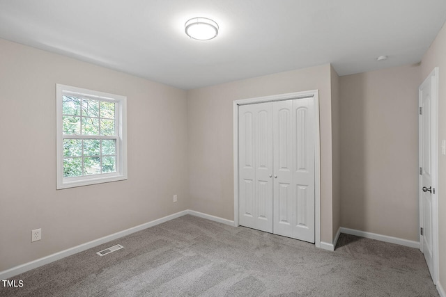 unfurnished bedroom with a closet and light colored carpet