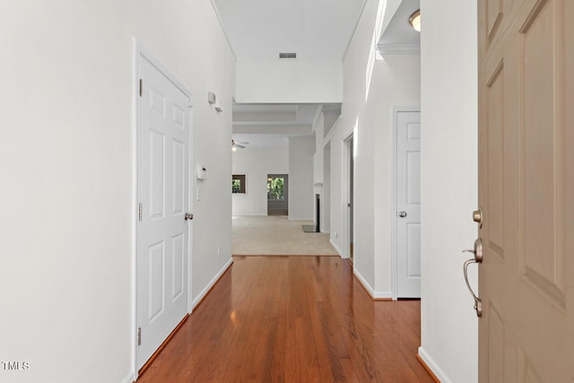 corridor with ornamental molding and hardwood / wood-style flooring