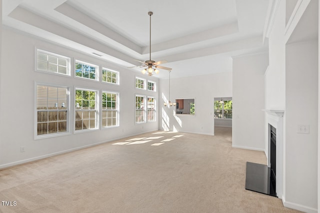 unfurnished living room featuring light carpet, a raised ceiling, a high ceiling, and ceiling fan