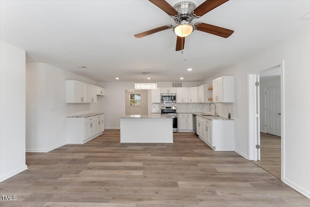 kitchen featuring white cabinets, light wood-type flooring, appliances with stainless steel finishes, and a center island