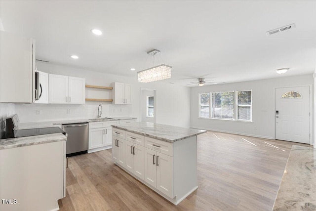 kitchen with stainless steel appliances, light wood-type flooring, white cabinetry, hanging light fixtures, and ceiling fan with notable chandelier