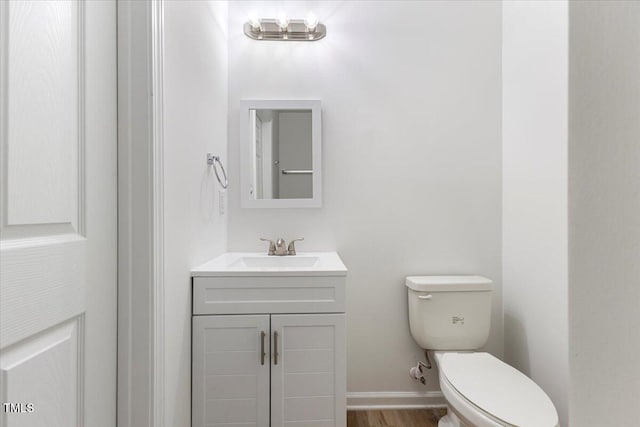 bathroom featuring wood-type flooring, toilet, and vanity