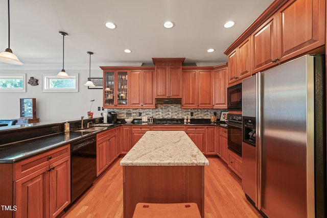 kitchen with dark stone counters, sink, black appliances, pendant lighting, and light wood-type flooring