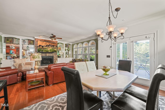 dining room featuring ornamental molding, hardwood / wood-style floors, and a stone fireplace