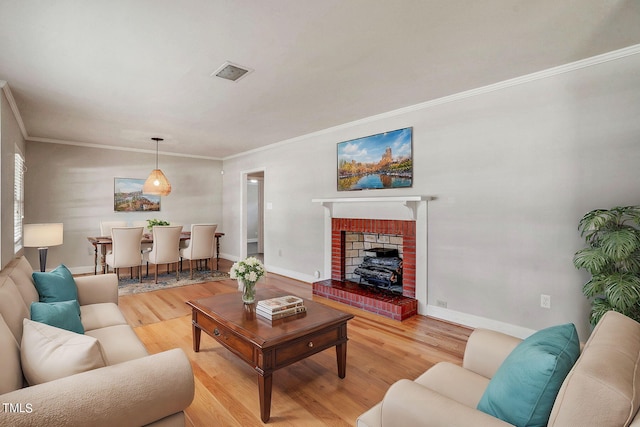 living room featuring ornamental molding, light wood-type flooring, and a brick fireplace