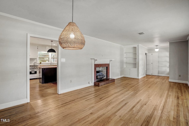 unfurnished living room with a brick fireplace, light hardwood / wood-style flooring, built in features, and ornamental molding