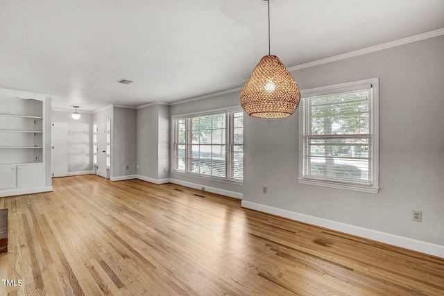 unfurnished dining area featuring crown molding, built in shelves, light hardwood / wood-style flooring, and a healthy amount of sunlight