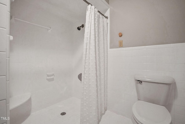 bathroom with tile walls, toilet, and curtained shower