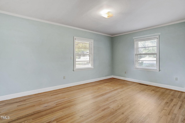 unfurnished room featuring light wood-type flooring, crown molding, and a wealth of natural light