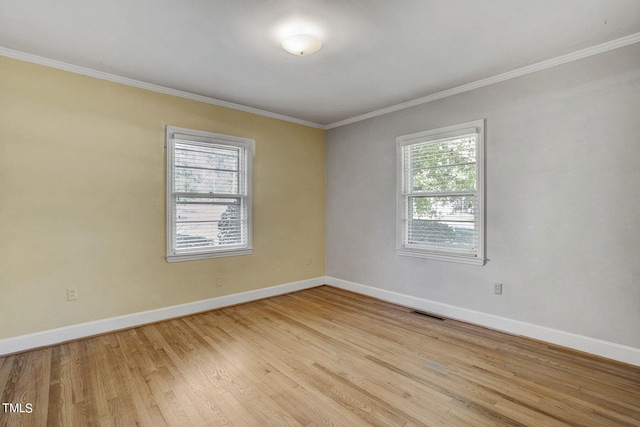 spare room with light wood-type flooring, crown molding, and plenty of natural light