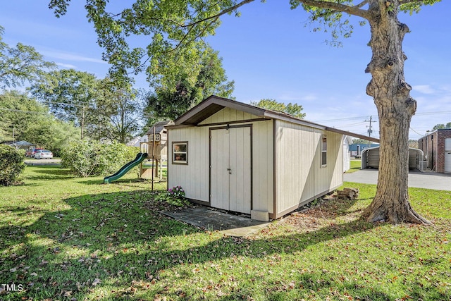 view of outbuilding with a playground and a lawn