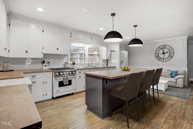 kitchen with white cabinets, wooden counters, white fridge with ice dispenser, high end range, and decorative light fixtures