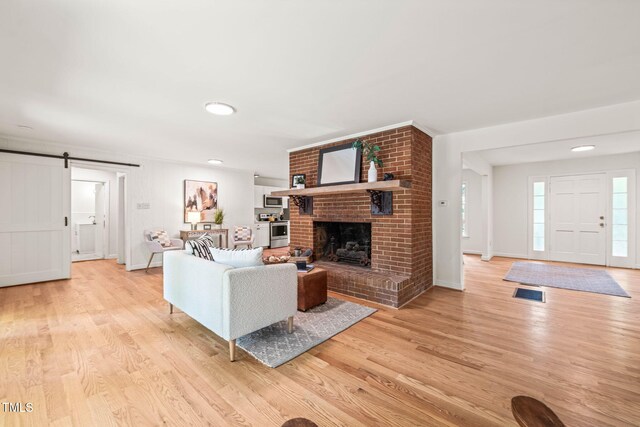 3006 Pump Station Ln, Durham, NC 27712 - living area with a barn door, light wood-type flooring, a fireplace, and recessed lighting