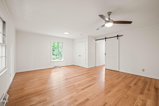 3006 Pump Station Ln, Durham, NC 27712 - unfurnished bedroom with crown molding, light wood finished floors, a barn door, a ceiling fan, and a closet