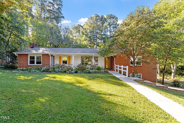 ranch-style house with brick siding, a chimney, and a front lawn