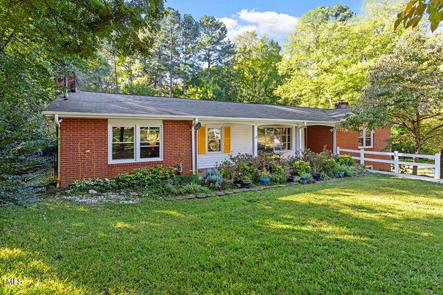 single story home with a front yard, a chimney, fence, and brick siding