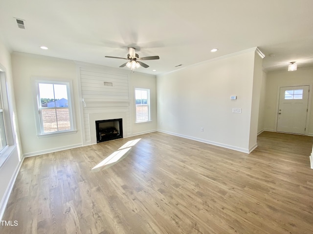 unfurnished living room featuring light hardwood / wood-style floors, a fireplace, ceiling fan, and plenty of natural light