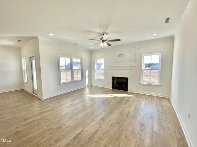 unfurnished living room featuring a large fireplace, ceiling fan, ornamental molding, and light hardwood / wood-style flooring