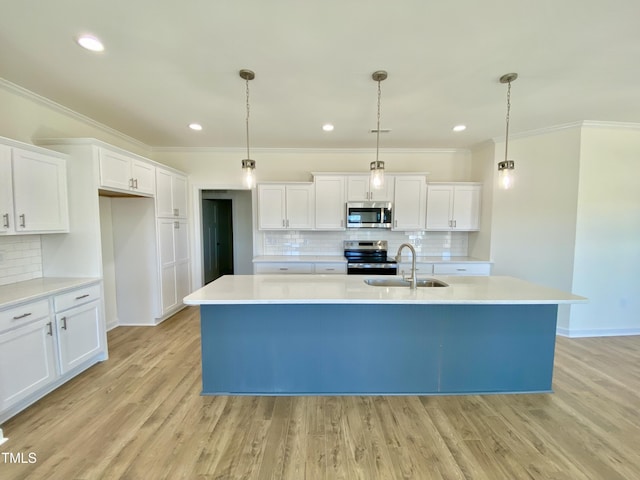 kitchen with stainless steel appliances, sink, white cabinetry, an island with sink, and pendant lighting