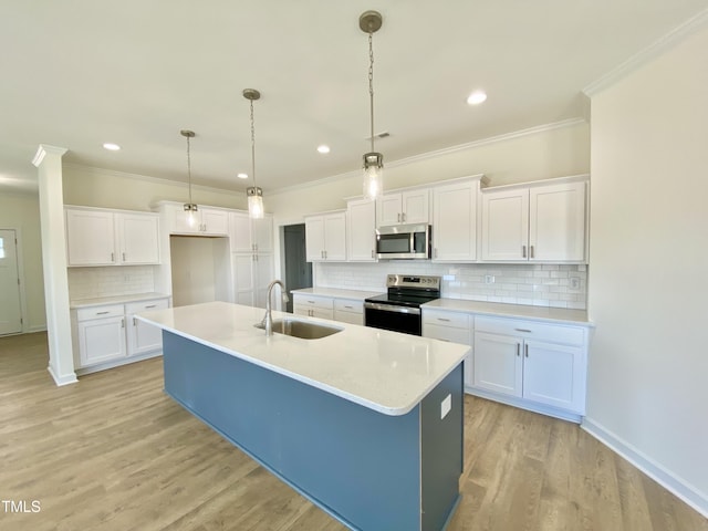 kitchen with a kitchen island with sink, appliances with stainless steel finishes, white cabinets, decorative light fixtures, and sink