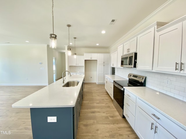 kitchen with an island with sink, appliances with stainless steel finishes, white cabinets, and sink