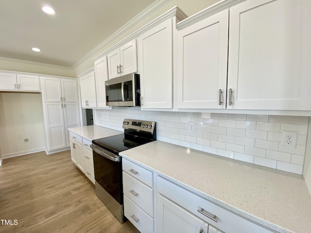 kitchen with light stone countertops, tasteful backsplash, crown molding, white cabinetry, and appliances with stainless steel finishes