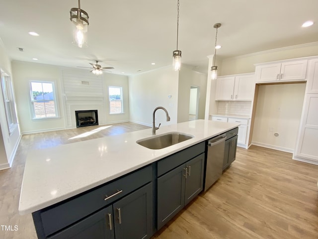 kitchen with sink, white cabinetry, dishwasher, a large fireplace, and backsplash