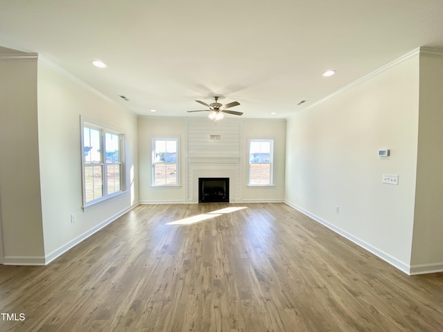 unfurnished living room with a large fireplace, hardwood / wood-style flooring, ceiling fan, and ornamental molding