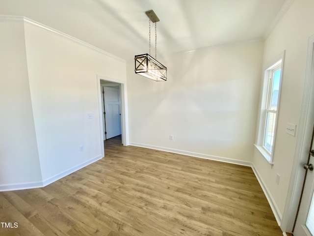 unfurnished dining area featuring an inviting chandelier, crown molding, and hardwood / wood-style floors