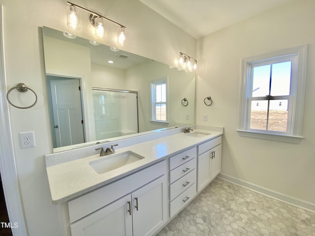 bathroom featuring a shower with door, vanity, and a healthy amount of sunlight