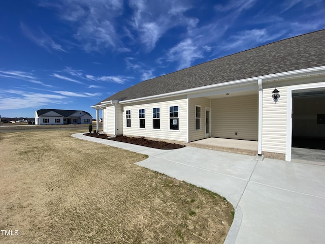 exterior space with a shingled roof, driveway, and a carport