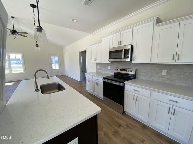 kitchen with decorative backsplash, vaulted ceiling, stainless steel appliances, white cabinetry, and a sink